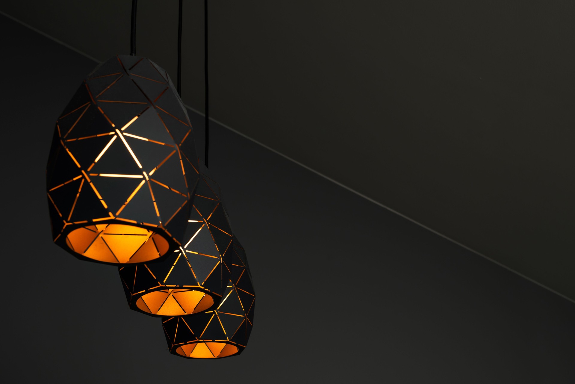 Black lamps with a geometric pattern, three lamps on a black background, burning with warm light, with a graphic pattern