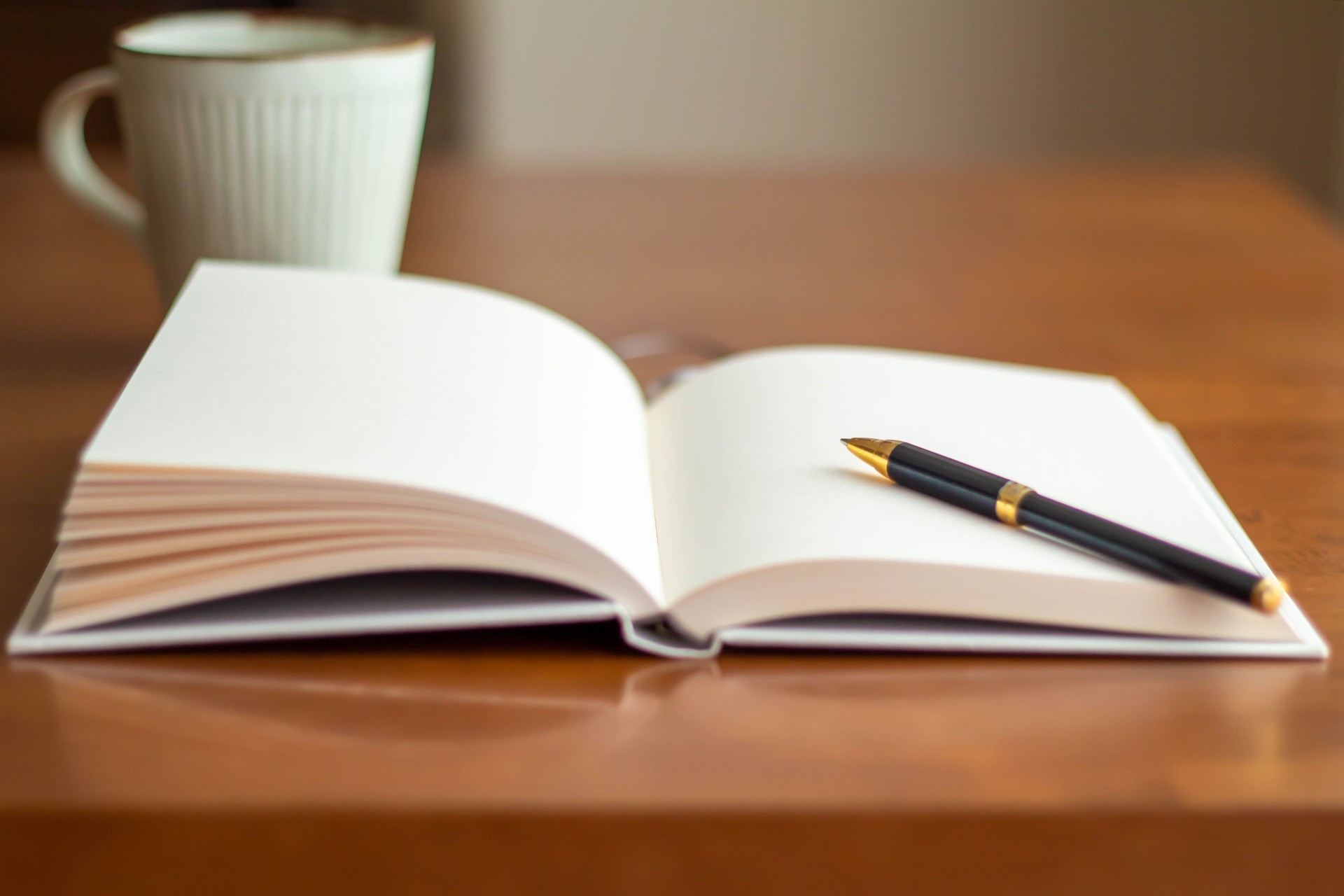 Close-up of a clean book on the table and a cup of ballpoint pen and coffee