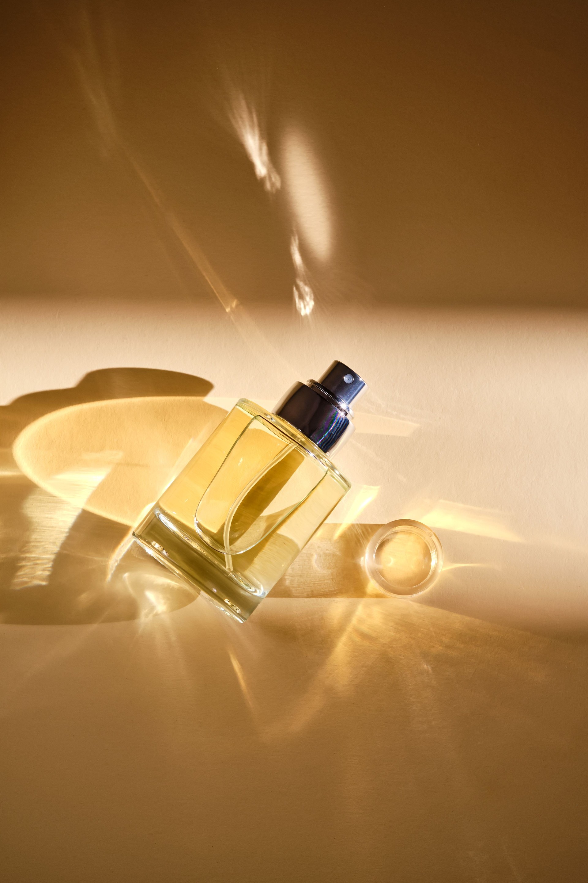 Perfume on a beige background in the rays of bright sun with beautiful highlights.